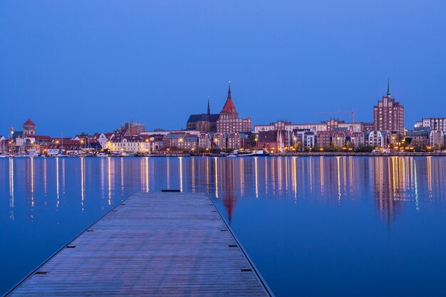 Foto verlicht stadsbeeld bij de zee tegen een heldere blauwe hemel's nachts