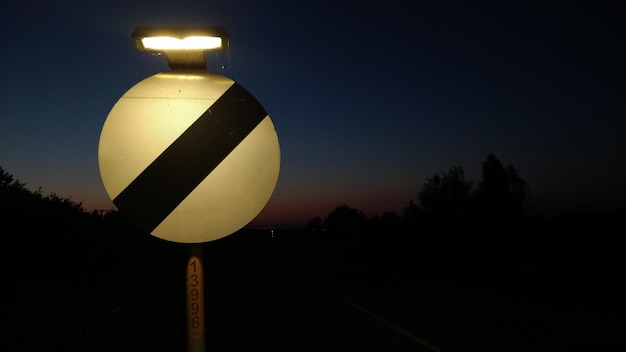 Verlicht verkeersbord tegen de hemel's nachts