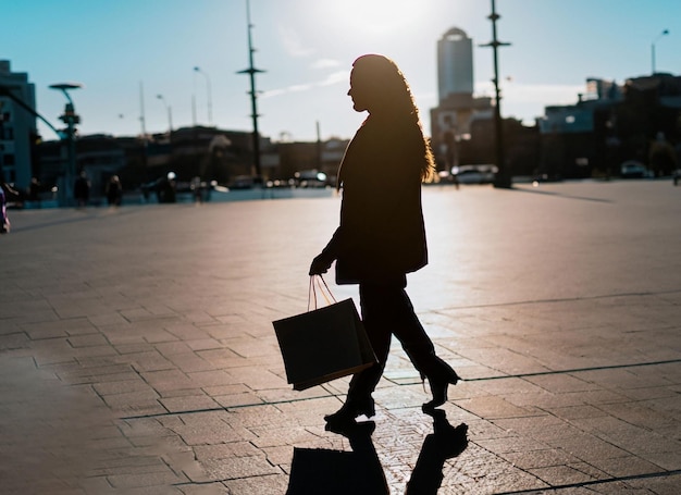 Verlicht vrouwensilhouet dat loopt met een papieren boodschappentas met kopieerruimte