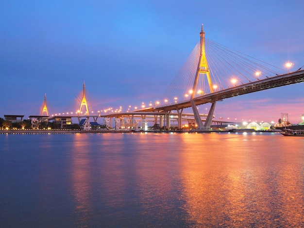 Verlichte brug over de rivier met de stad op de achtergrond
