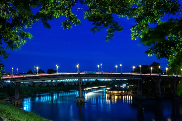 Verlichte brug over de rivier tegen de blauwe hemel's nachts
