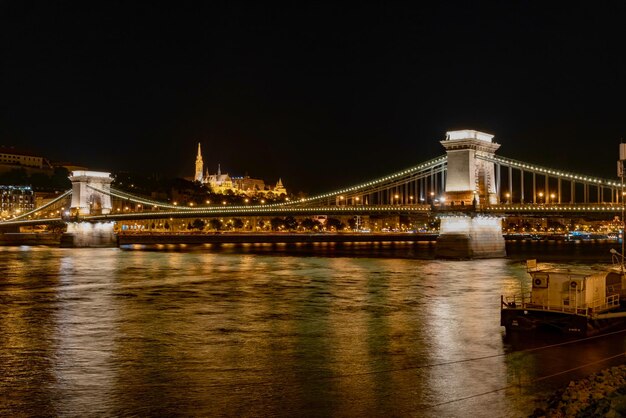 Verlichte brug over de rivier tegen de hemel 's nachts