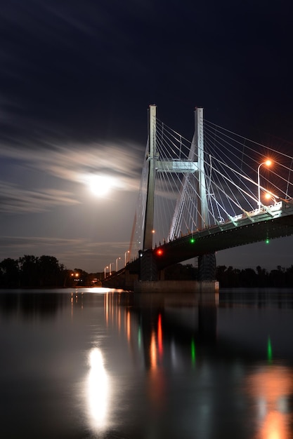 Foto verlichte brug over de rivier tegen de hemel's nachts