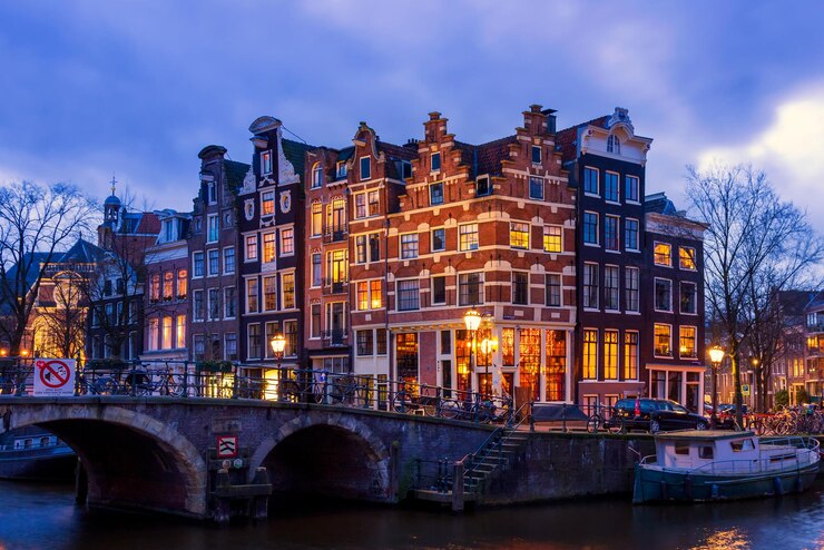 Foto verlichte brug over het kanaal door gebouwen tegen de lucht in de stad