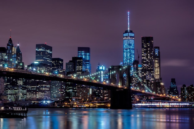 Verlichte gebouwen en de Brooklyn Bridge tegen de hemel's nachts