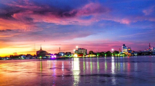 Foto verlichte gebouwen langs de rivier tegen de hemel bij zonsondergang