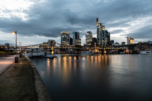 Foto verlichte gebouwen langs de rivier tegen een bewolkte lucht