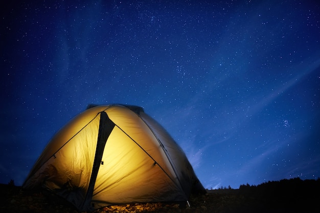 Verlichte gele campingtent 's nachts onder de sterren