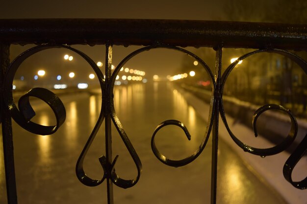 Foto verlichte lichten langs een wazig meer met relingen op de voorgrond