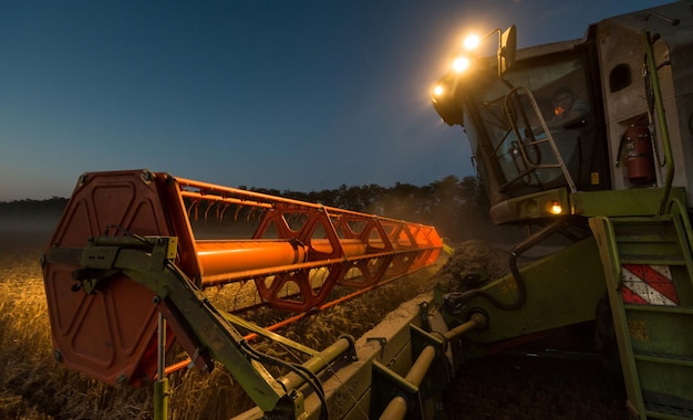 Verlichte machine oogst gewassen op het veld in de schemering