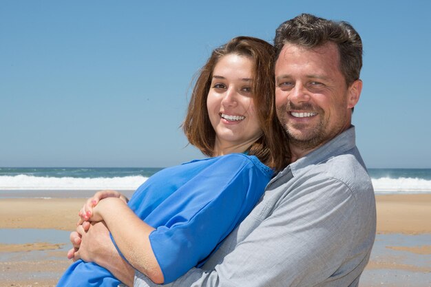 Verliefd stel dat samen naar de camera kijkt op het zomerstrand