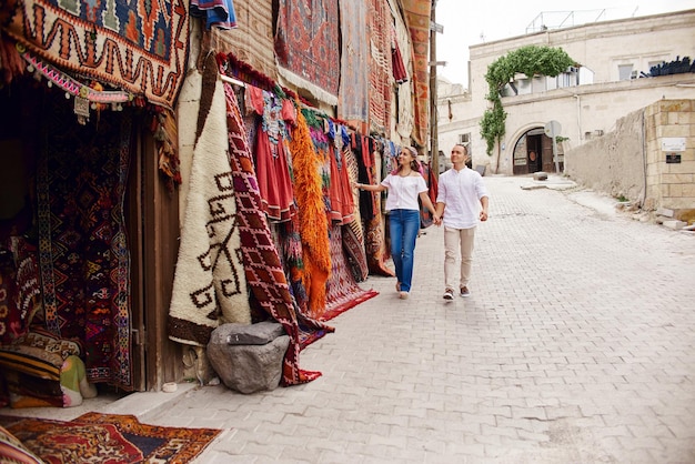 Verliefd stel koopt een tapijt en handgemaakt textiel op een oosterse markt in Turkije. Knuffels en vrolijke blije gezichten van mannen en vrouwen