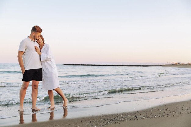 Verliefd stel met romantische tedere momenten bij zonsondergang op het strand Jonge geliefden met tedere moeder