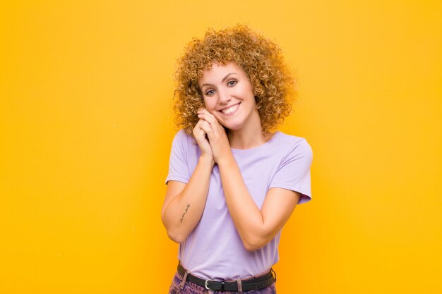 verliefd voelen en er schattig, schattig en gelukkig uitzien, romantisch glimlachend met de handen naast het gezicht