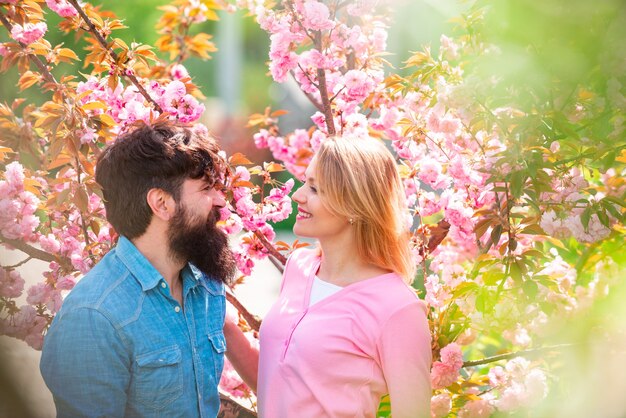 Verliefde paar genieten van zonnige dag in het park tijdens kersenbloesemboom