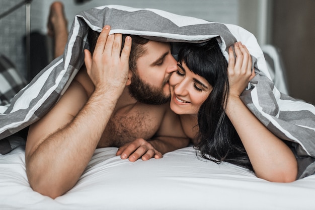 Verliefde paar in bed seks. Jongen en meisje kussen in bed. Huwelijksnacht. De liefde bedrijven. Liefhebbers in bed. De relatie tussen een man en een vrouw. Seks tussen een man en een vrouw. Knuffels in bed.