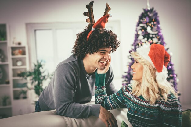 Verliefde paar in gezellige warme truien op een kerst - oudejaarsavond, glimlachend en plezier met elkaar.