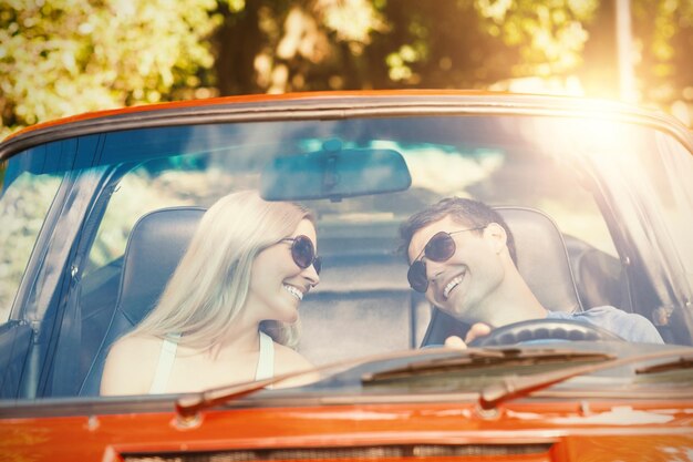 Verliefde paar in hun rode cabriolet met een ritje op een zonnige dag