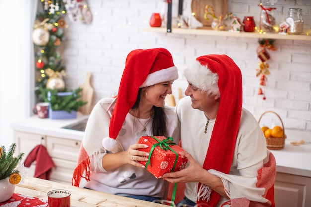 Verliefde paar in Santa hoeden geschenken op Kerstmis