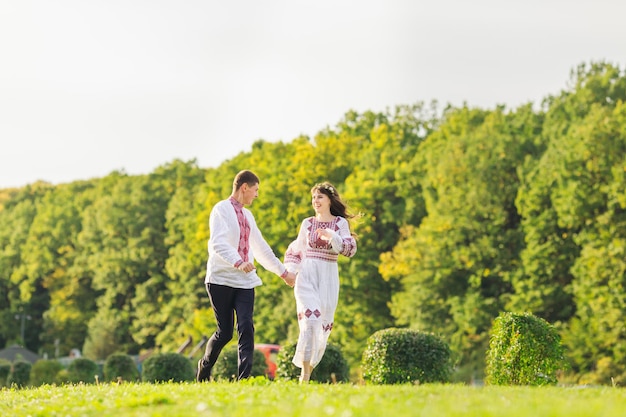 Verliefde paar kijken elkaar aan in het park en rennen hand in hand met de natuur