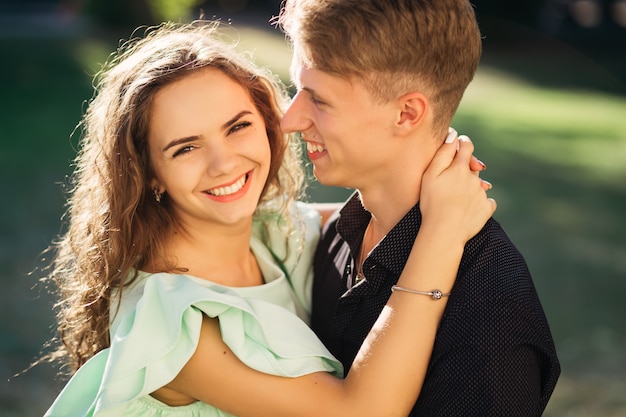 Verliefde paar knuffelen en lachen in het park op een zonnige zomerdag