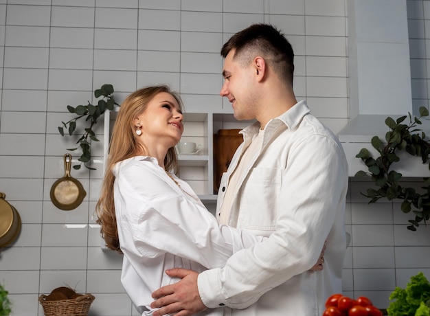 Verliefde paar knuffelen in de keuken tijdens het koken knappe man en mooie vrouw kijken elkaar aan