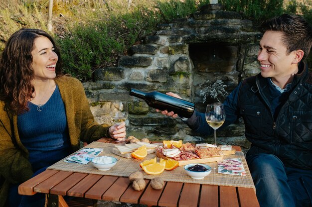 Verliefde paar met een aperitief buiten in de tuin, proeverij van rode wijn
