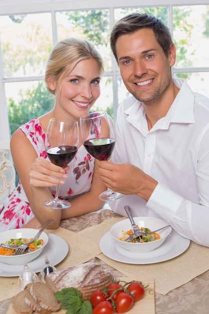 Verliefde paar met wijnglazen zitten aan de eettafel