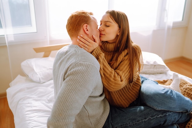 Verliefde paar ontspannen thuis op bed terwijl ze elkaar omhelzen Valentijnsdag vakantieconcept