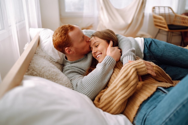 Verliefde paar ontspannen thuis op bed terwijl ze elkaar omhelzen Valentijnsdag vakantieconcept