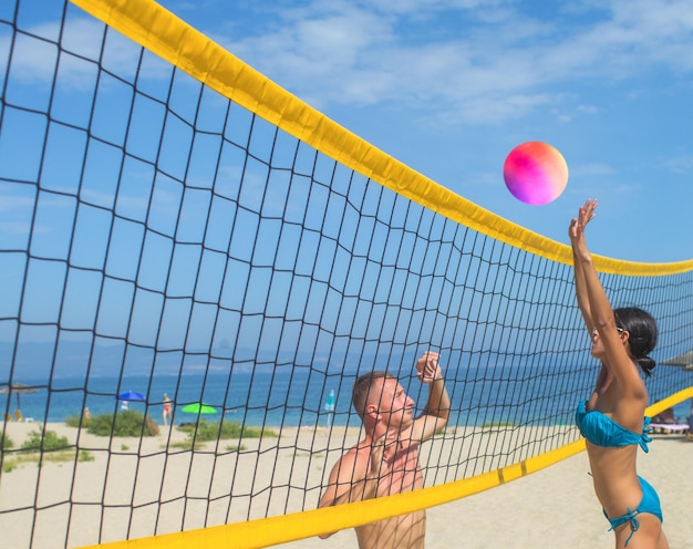 Verliefde paar spelen volleybal op zonnig strand Sexy mensen met bal op net Zomervakantie en reizen op vakantie in Miami Sportactiviteit en gezondheid