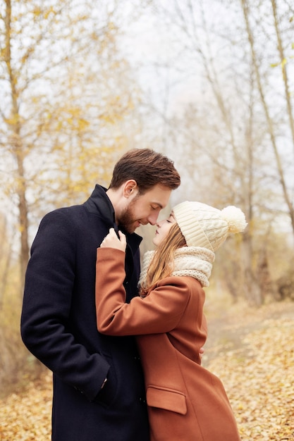 Verliefde paar wandelen in het herfstpark, koel herfstweer. Een man en een vrouw omhelzen en kussen, liefde en genegenheid, geel herfstlandschap