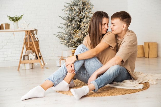 Foto verliefde paar zit op de grond in hun huis glimlachend en knuffels