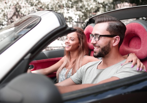 Verliefde paar zittend op de voorbank van een cabriolet