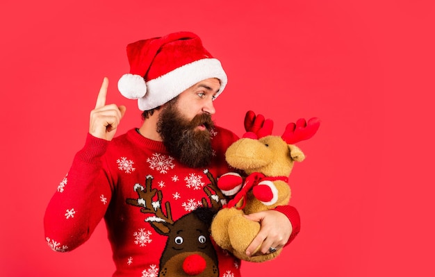 Verloren in kerstgedachten Kerstfeest man met rendier speelgoed gelukkige kerel wacht op nieuwjaarscadeau