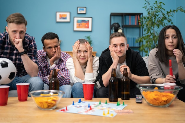 Verloren wedstrijd overstuur vrienden voetbal kijken en drinken thuis zittend op een bank