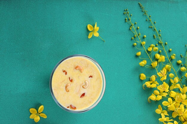 Vermecelli Payasam или Kheer, основное сладкое блюдо Южной Индии, приготовленное с использованием вермишели, молока, сахара и сухих орехов и украшенное цветком золотого дождя на окрашенном зеленом фоне, выборочный фокус.