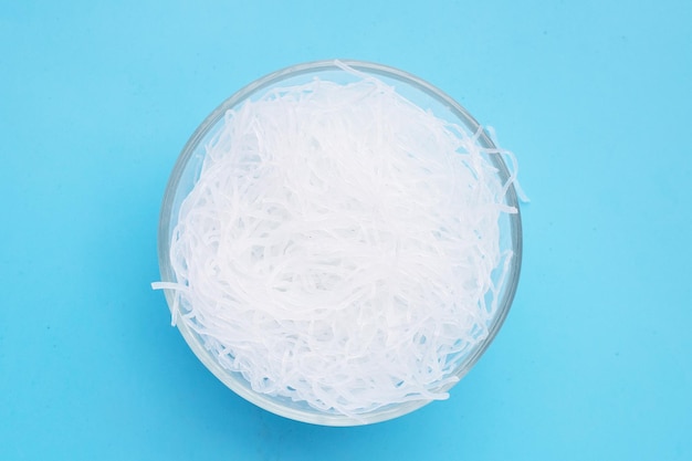 Vermicelli in glass bowl on blue background