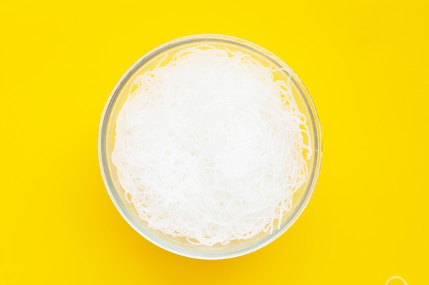 Vermicelli in recipiente di vetro su sfondo giallo