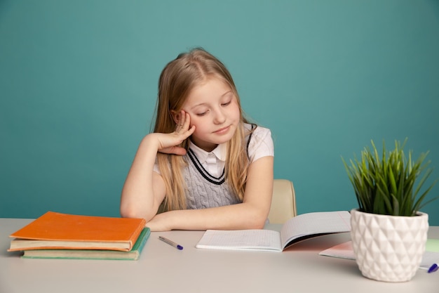 Vermoeid tienermeisje met boeken op de achtergrond van een schoolbestuur dat naar de camera kijkt Ruimte voor tekst