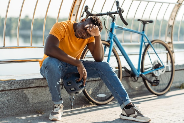 vermoeide Afrikaans-Amerikaanse man die wegkijkt terwijl hij ontspant na het fietsen