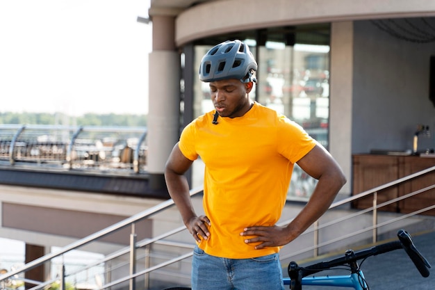 Vermoeide Afro-Amerikaanse man die bij zijn fiets op straat staat