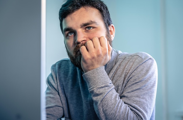 Vermoeide bebaarde man kijkt naar het computerscherm