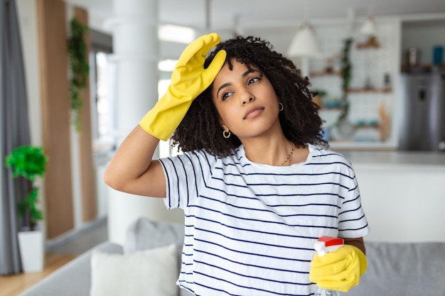 Vermoeide en uitgeputte vrouw die gefrustreerd is omdat ze veel werk aan het huis doet, een minuut rust of haar voorhoofd afveegt na het beëindigen van het werk Huishoudconcept