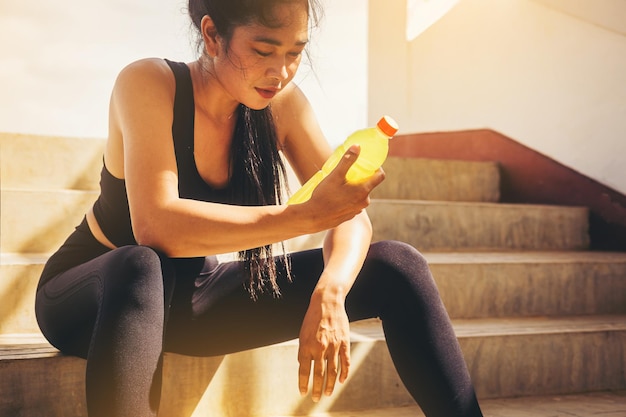 Vermoeide hardloper vrouw met een fles elektrolyt drinken frisheid na training buiten training