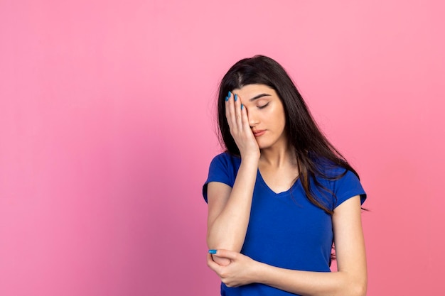 Vermoeide jonge vrouw die haar handen op haar gezicht legt en op een roze achtergrond staat Hoge kwaliteit foto