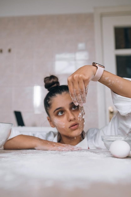 Vermoeide jonge vrouw giet meel op de keukentafel