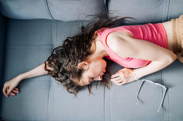 Vermoeide jonge vrouw met lang haar die op de bank slaapt.