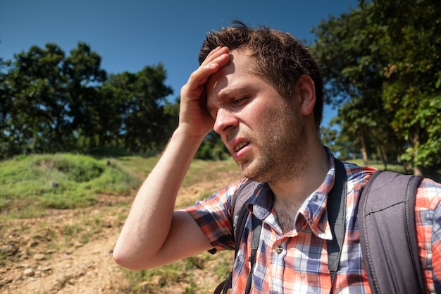 Vermoeide man in bos onder sterke zon met rugzak Alleen reizen in Azië Lijd aan een zonnesteek