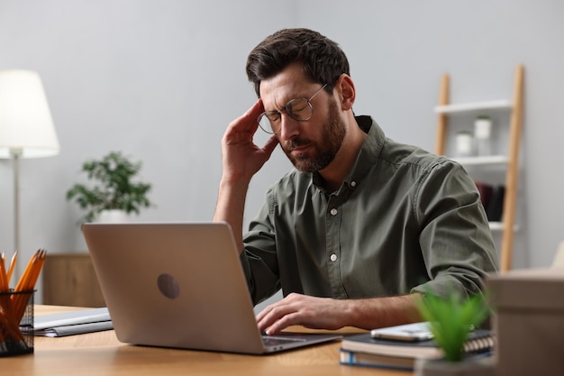 Vermoeide man met hoofdpijn op de werkplaats